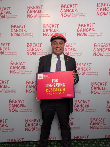 Wearing it Pink for Breast Cancer Awareness! David wearing a pink hat and holding a sign supporting life-saving breast cancer research